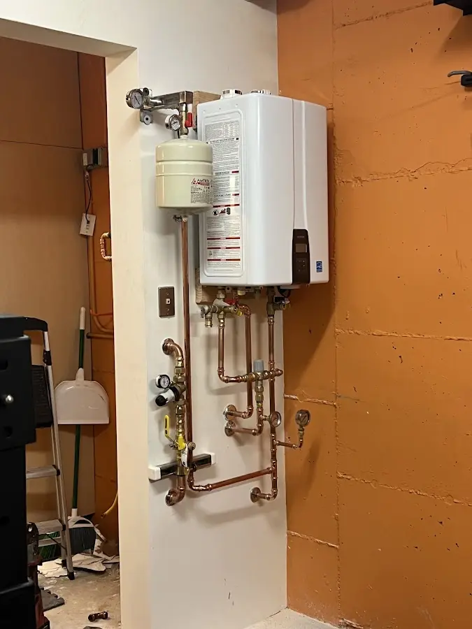 Plumbing technician inspecting water heater connections in Canton